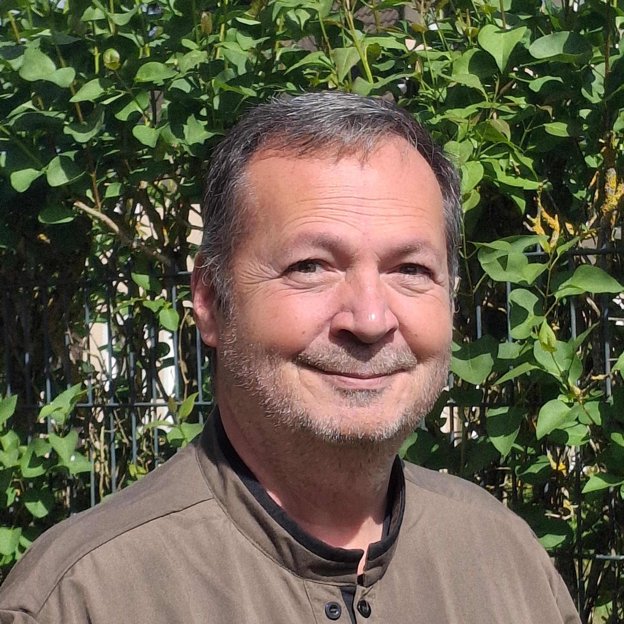 Pfarrer in Zivilkleidung, braunes Hemd, schwarze Haare